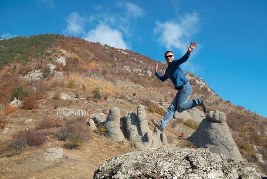 Man jumping on the rocks with landscape background