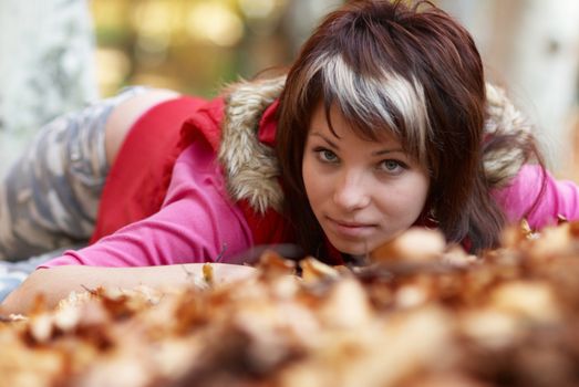 Beautiful girl's portrait with leaves in the autumn park