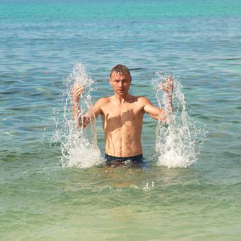 Happy man in the tropical sea with splashes