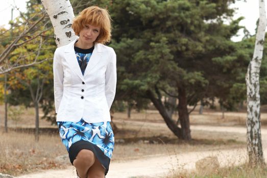 Beautiful woman standing near birch with soft background