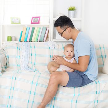 Tired father taking care baby alone at home. Asian family lifestyle at home.