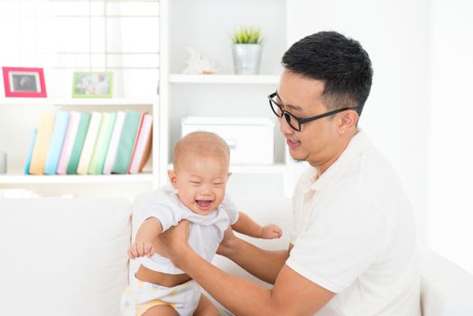 Happy father and baby boy playing at home. Southeast Asian family lifestyle indoors.