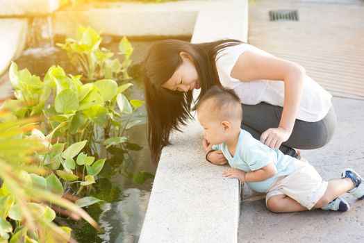 Asian mother and kid having fun time at outdoor in sunset during vacations.