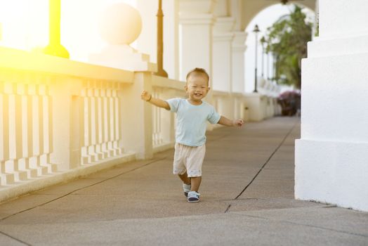 Portrait of baby boy running and smiling outdoor in sunset.