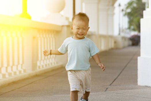 Portrait of young kid running and smiling outdoor in sunset.
