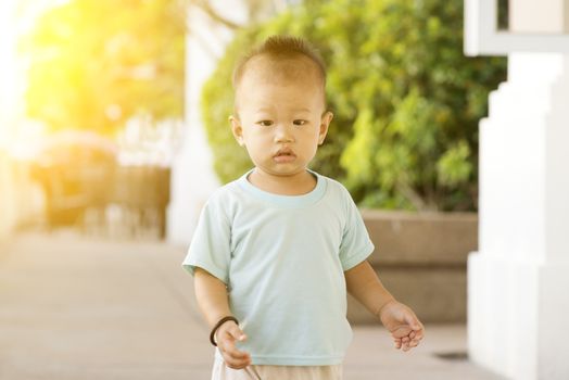 Portrait of Asian toddler walking outdoor in sunset.