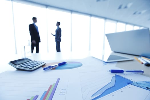 Financial reports, calculator and laptop on table in office