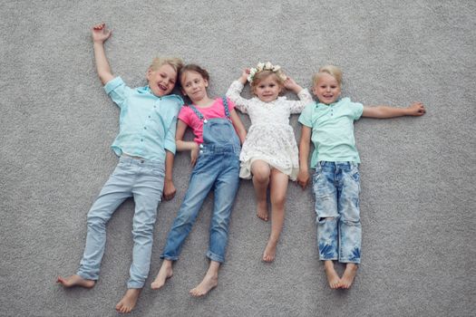 Group of happy kids laying on floor, top view