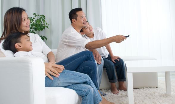 Asian family watching television at home