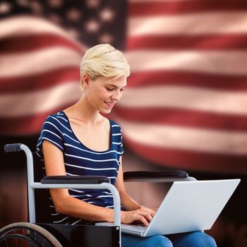 Woman in wheelchair using computer against composite image of digitally generated united states national flag