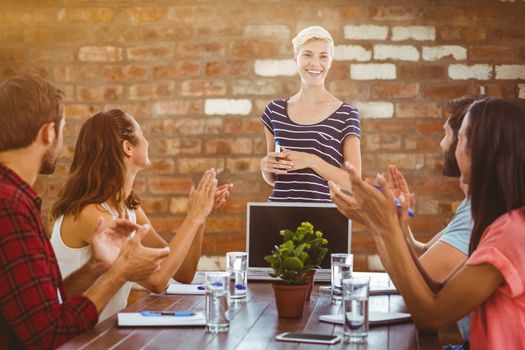 Colleagues clapping hands in a meeting against brick wall