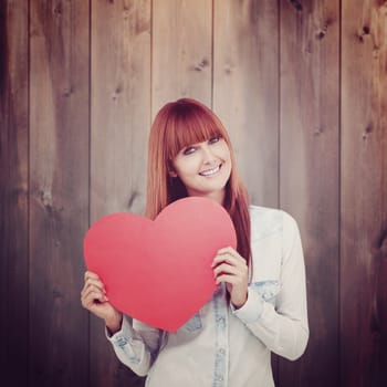 Attractive hipster woman behind a red heart against wooden planks