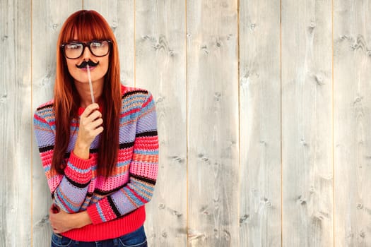 Smiling hipster woman with a mustache against pale wooden planks