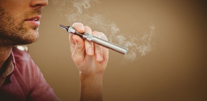 Cropped image of man smoking electronic cigarette against grey background with vignette