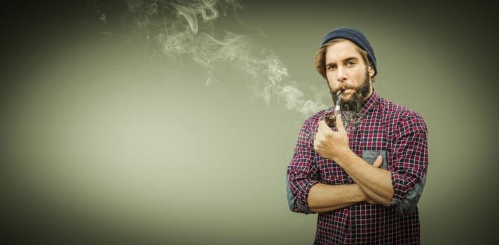 Hipster wearing knitted hat smoking pipe against grey vignette