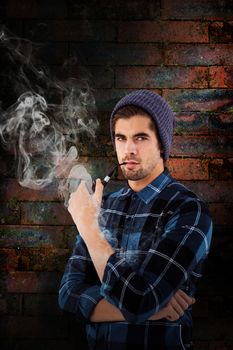 Portrait of hipster holding smoking pipe against texture of bricks wall