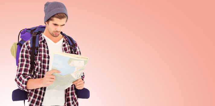 Man with luggage looking in map against salmon background
