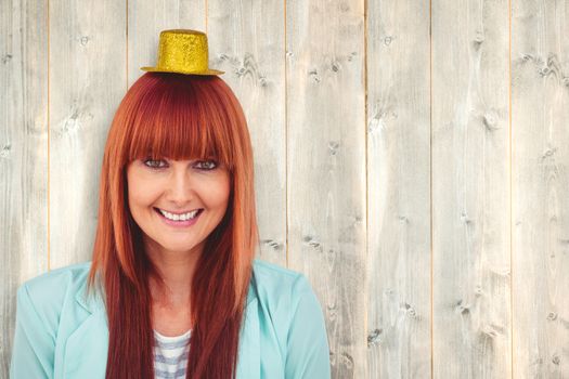 Smiling hipster woman wearing hat party against pale wooden planks