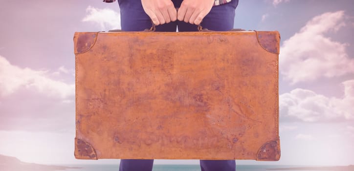 Mid section of man holding briefcase against beach