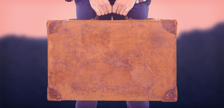 Mid section of man holding briefcase against blurred mountains