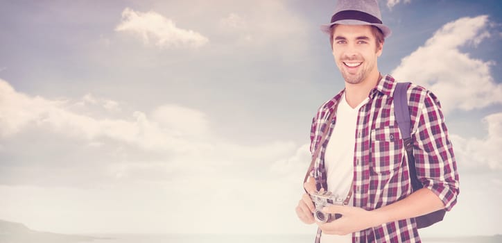 Portrait of man smiling while holding camera against beach