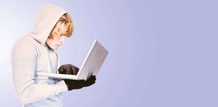 Focused man with hoodie typing on laptop against pastel blue