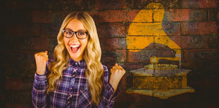 Gorgeous blonde hipster celebrating success against texture of bricks wall