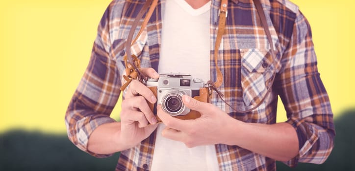 Mid section of hipster using camera against blurred mountains