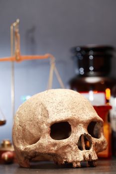 Medical laboratory. Human skull on blurred background with weight scale and flasks