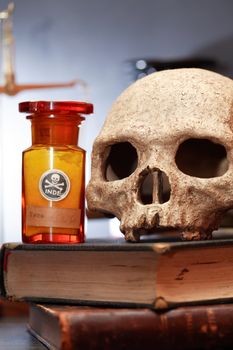 Medical laboratory. Human skull on old book near flask with poison