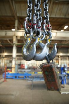 The steel hooks hanging on the background of industrial premises

