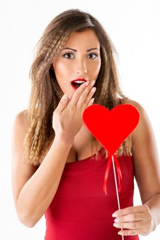 Beautiful surprised smiling girl holding a red heart. Looking at camera.