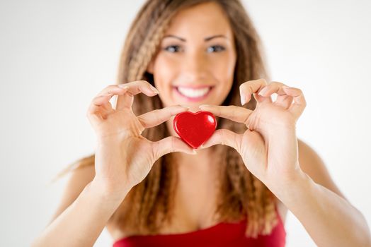Beautiful smiling girl holding a red heart. Selective focus. Focus on the heart.