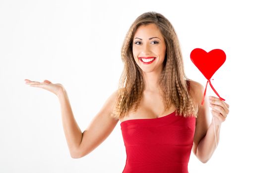 Beautiful smiling girl standing and holding red heart. Looking at camera.
