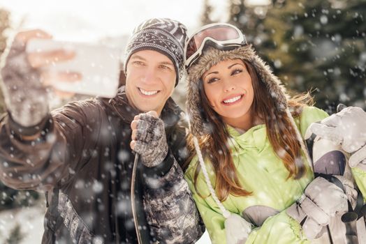 Portrait of a beautiful smiling couple taking selfie on winter vacations. 