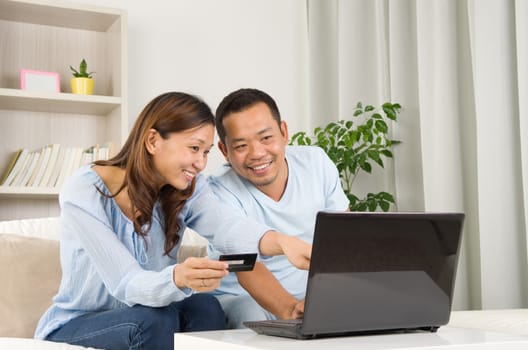 Asian couple using laptop to perform online shopping