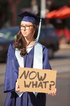 Sad young graduate in blue holding cardboard sign