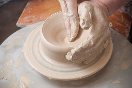 Hands of a potter, creating an earthen jar on the circle