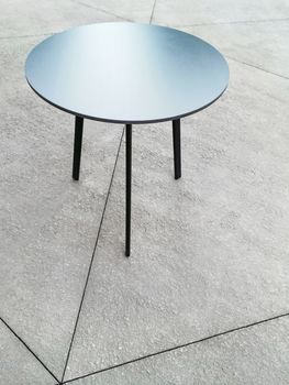 Round metal table on concrete floor. Modern design.