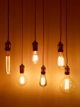 Illuminated light bulbs on warm orange background. Modern design with retro feel.