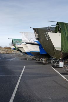 many boat on storage for the winter on the parking with between the pier