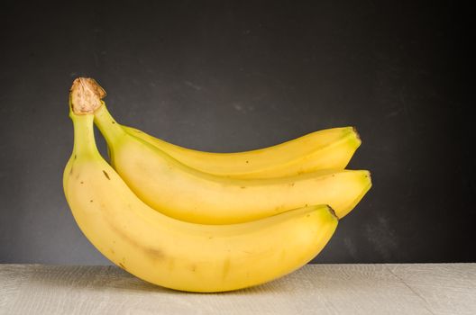 Fresh bananas on wooden background. Black chalkboard background