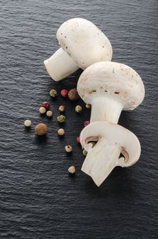 Fresh mushrooms with spices and herbs on a black board.