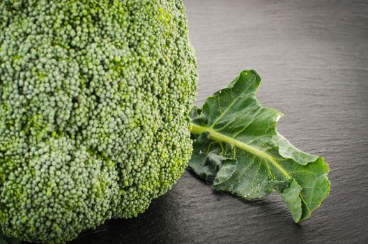 Raw broccoli on black chalkboard. Background with free text space.