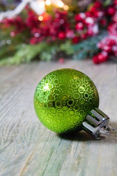 A green Christmas decoration ornament on a wooden background.