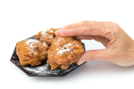 Hand showing dutch oliebol or fritter with icing sugar isolated on white background