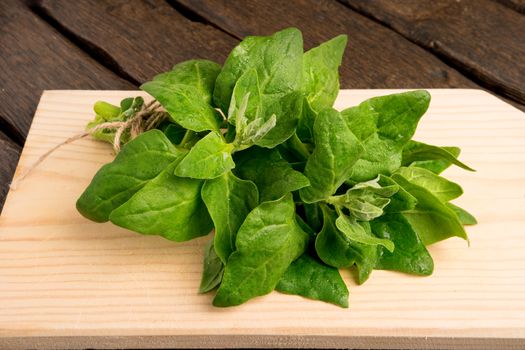 Spring spinach leaves on cutting board and dark wooden background
