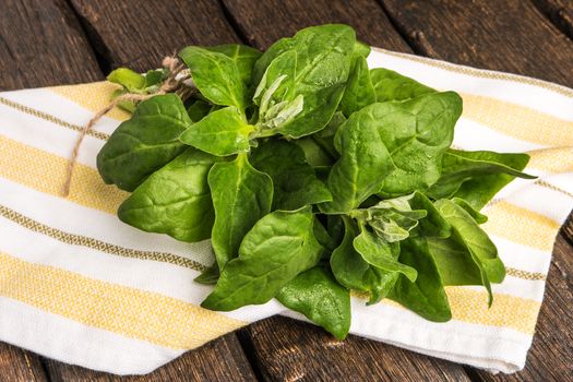 Spring spinach leaves on dark wooden background with kitchen cloth