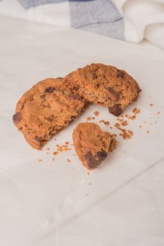 Chocolate chip cookies with a blue ribbon and a glass of milk with a straw on a white wooden table with a robin egg blue background. Vintage look.