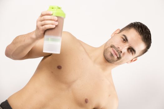 athletic young man with protein shake bottle. on white background